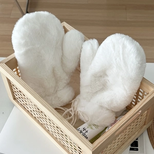 Close-up of white plush mittens with lanyard in a wooden basket for a cozy winter vibe