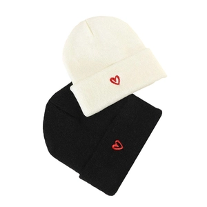 Winter knitted beanies in black and white with red heart embroidery detail for cold weather
