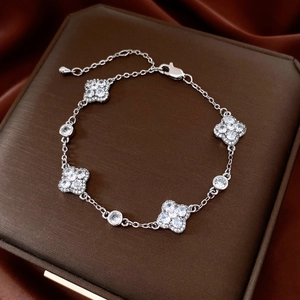 Macro detail of silver four-leaf clover bracelet with sparkling zircon stones on silk