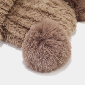 Gros plan d'un grand pompon en fourrure synthétique marron sur un accessoire de tricot