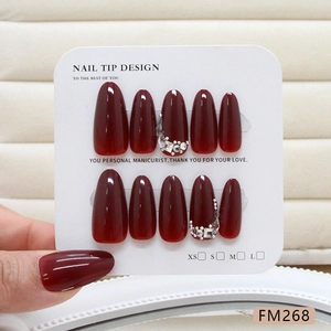 Handmade wine red press-on nails with sparkling diamonds and pearls on a white display card