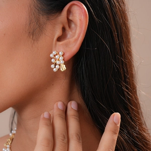 Detail shot of vintage flower leaf pearl earrings in gold finish on a model