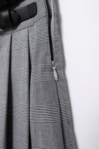 Détail d'une mini-jupe plissée à motif pied-de-poule avec boucle de ceinture et fermeture
