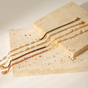 Close-up of gold stainless steel link bracelets with colorful zircon stones on stone tray