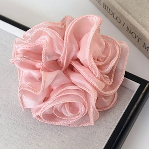 Detail of pink floral scrunchie showing delicate pearlescent organza fabric and soft petals