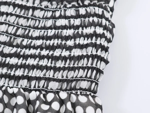 Detail of smocked elastic waist and black polka dot chiffon fabric on the dress