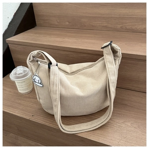 Detail of beige corduroy crossbody bag with adjustable strap and cloud plush pendant