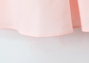 Detailed macro view of pink dress hem featuring layered plain fabric and soft tulle mesh