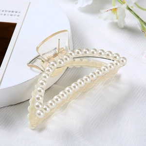 Detailed close-up of pearl embellished hair claw clip on minimalist white background