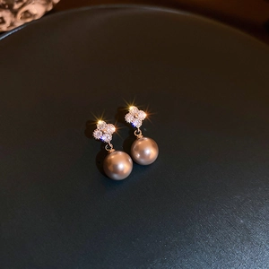 Detailed view of zircon clover earrings with champagne pearls and sparkling starburst effects