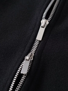 Close-up of dual silver metal zippers on black wool blend jacket fabric texture
