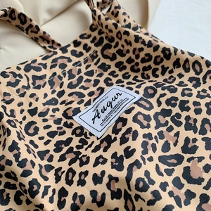 Close-up of leopard print tote bag fabric texture with stitched brand label