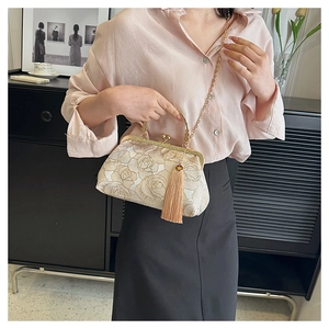 Detailed embroidery of gold roses on an ivory crossbody bag with elegant fringe and chain