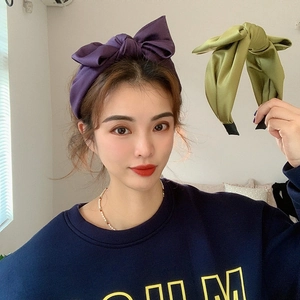 Close-up of purple and green satin bow headbands showing silky texture and large bow style