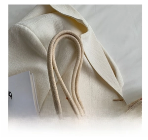 Detail of round rope handle and textured woven fabric on a summer beach tote bag