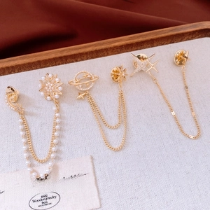 Macro detail of 14K gold plated Saturn chain brooch with delicate pearls and crystals