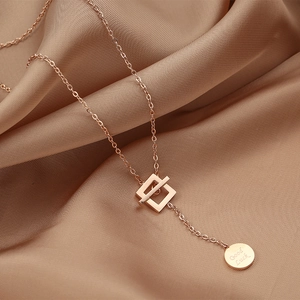 Detailed close-up of rose gold Love necklace with Good Luck pendant on beige silk