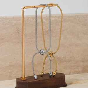 Adjustable gold and silver snake chain bracelets with sliding clasp on display stand