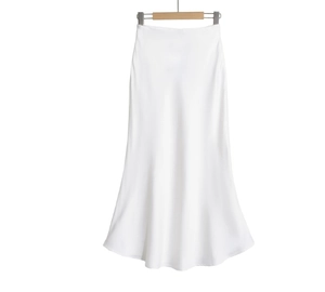 Détail macro du tissu en satin blanc de la jupe longue à taille haute avec ourlet fluide