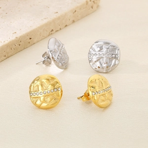 Detailed macro view of gold and silver textured round earrings with sparkling zircon row