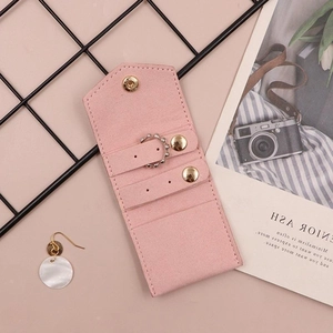 Detailed flat lay of a pink suede jewelry pouch with ring holder and button snap closure