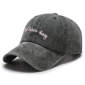 Close-up of pink Bad Hair Day embroidery on washed dark grey cotton baseball cap