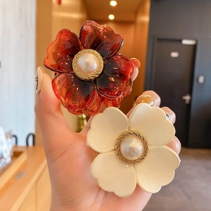 Detail of amber and cream flower hair clips with pearl centers in a vintage French style