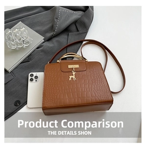 Brown crocodile pattern crossbody bag with golden handle and deer charm next to a phone