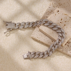 Dettaglio di un bracciale a catena cubana argento con diamanti su sfondo in pietra