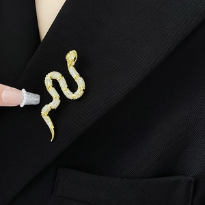 Luxury gold plated snake brooch with white zircons pinned on a black suit lapel