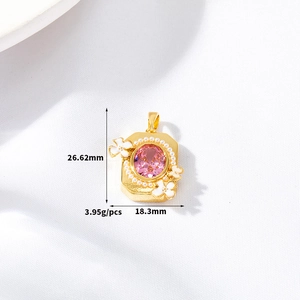 Detailed view of a gold square pendant with pink gemstone and white enamel flowers