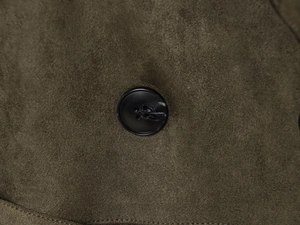 Detailed close-up of a black resin button on olive green faux suede coat fabric