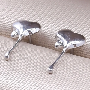 Close-up of heart-shaped stainless steel earrings with a fluid, glossy finish in a box