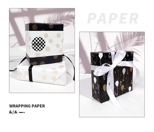 Detail of polka dot and balloon gift wrapping paper on boxes with palm leaf shadows