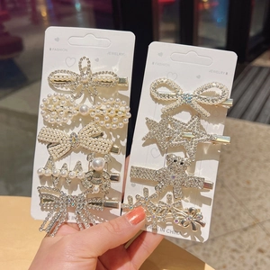 Close-up of golden hair clips set with sparkling rhinestones and pearls on display cards