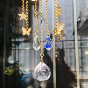 Detail of crystal suncatcher with gold butterfly, star charms and blue drop prism