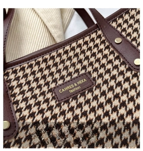 Detail of houndstooth tote bag featuring premium leather trim and gold rivet accents