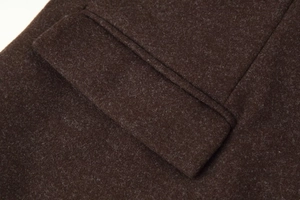 Macro detail of deep brown wool coat pocket showing high-quality fiber texture and stitching