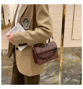 Détail du sac bandoulière matelassé marron foncé avec une grosse chaîne en résine et similicuir