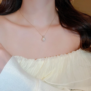 Close-up of a single round white pearl necklace with gold chain on woman neck