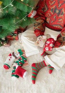 Cosy Christmas coral fleece socks with festive patterns on a white plush carpet background