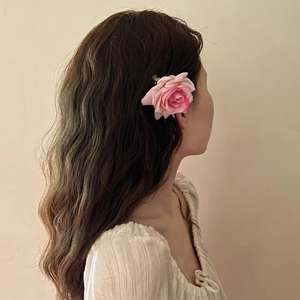 Side view of a pink fabric rose hair clip worn by a model to secure hair elegantly