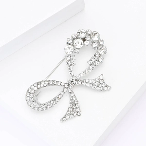 Close-up of elegant silver bow brooch with sparkling rhinestones on white display