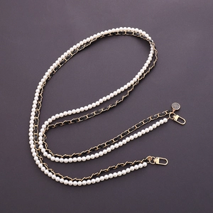 Detail of white faux pearl and gold metal chain strap with black ribbon and camellia charm