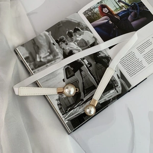 Detail of white elastic pearl belt with gold clasp and large faux pearls on leather ends