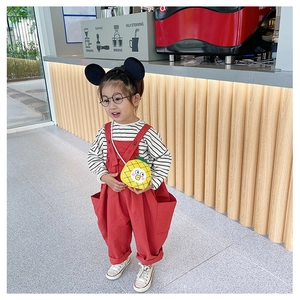 Detail of red overalls paired with a yellow pineapple bag and Mickey ears headband
