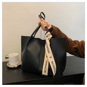 Detail of black tote bag with fashion webbing strap and matte leather texture finish