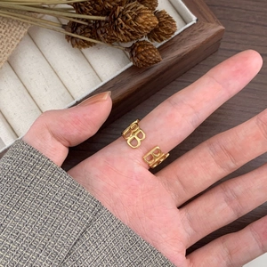 Detailed view of the gold-toned BB letter open ring worn on a finger