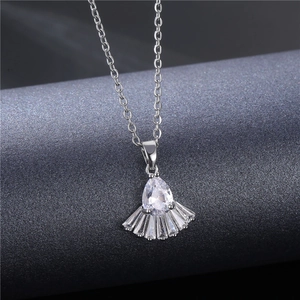 Silver necklace with fan-shaped cubic zirconia pendant on textured grey background
