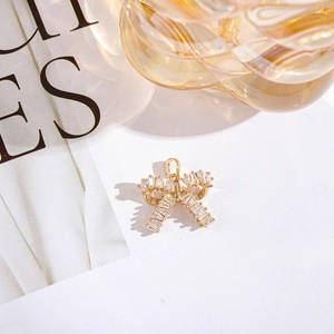 Macro shot of a gold bow pendant with zircon crystals on a stylish magazine background